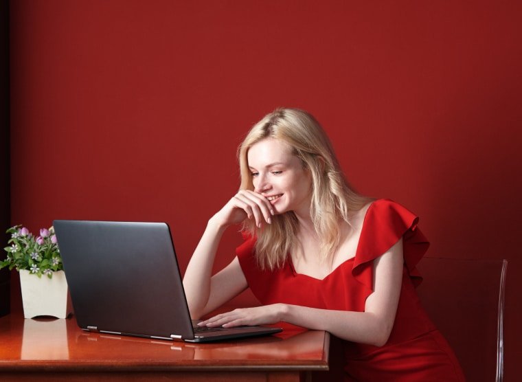 Person in red background sitting at the computer